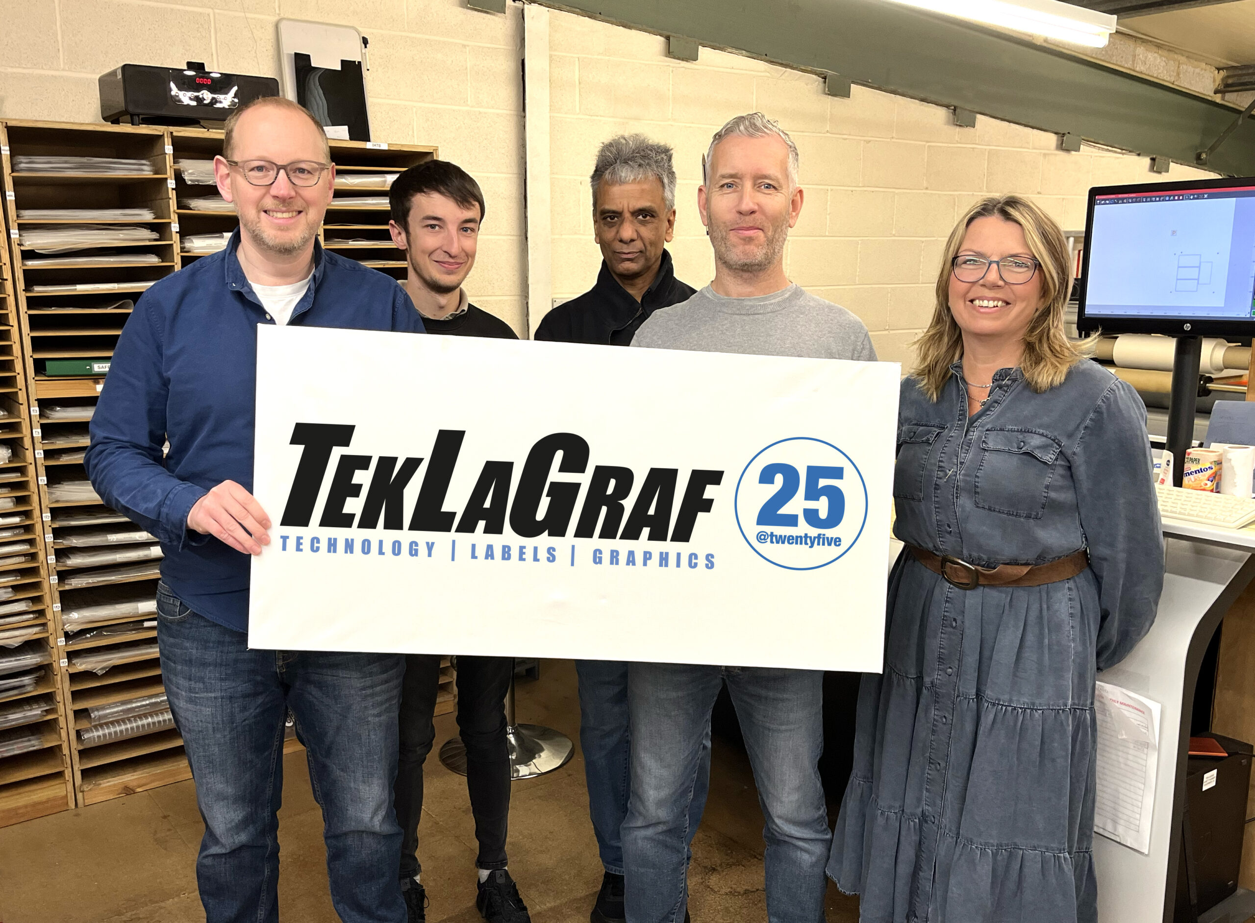 Teklagraf team holding 25 year sign